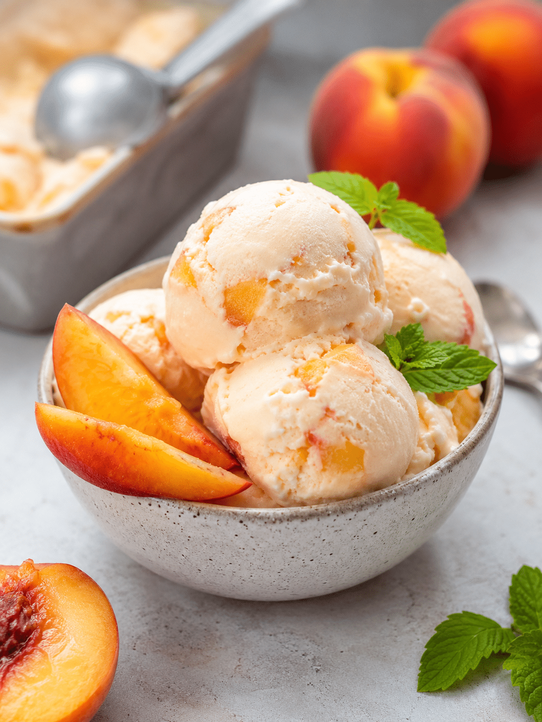 Fresh Peach Frozen Yogurt That's Creamy, Bright, and Easy 1 Fresh Peach Frozen Yogurt scooped into a bowl with ripe peach slices